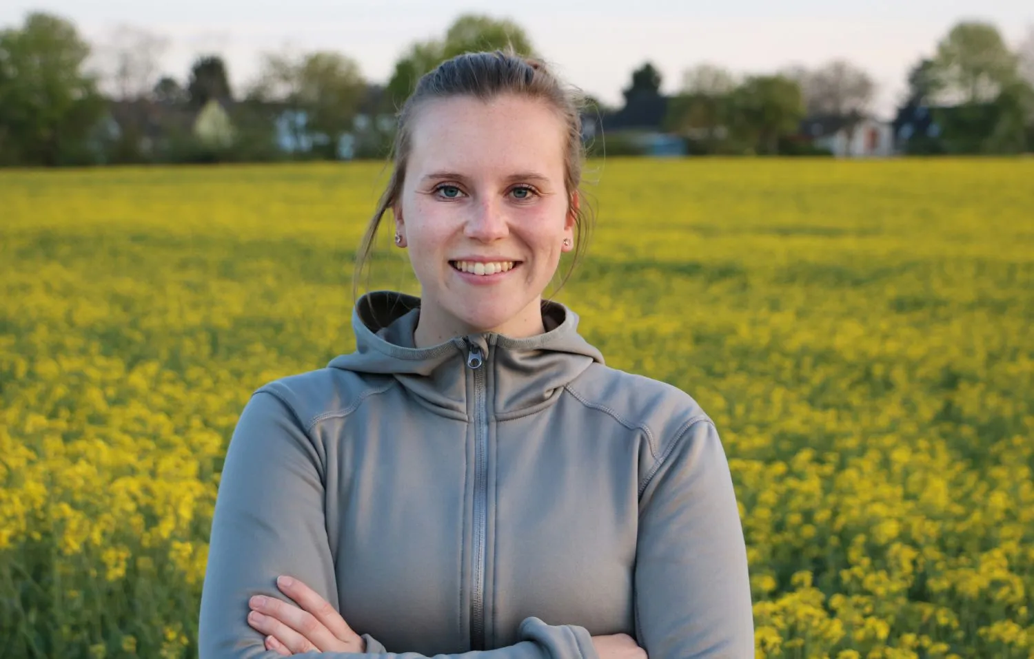 Julia Blum, Personal Trainerin aus Köln, lächelt in einem Rapsfeld